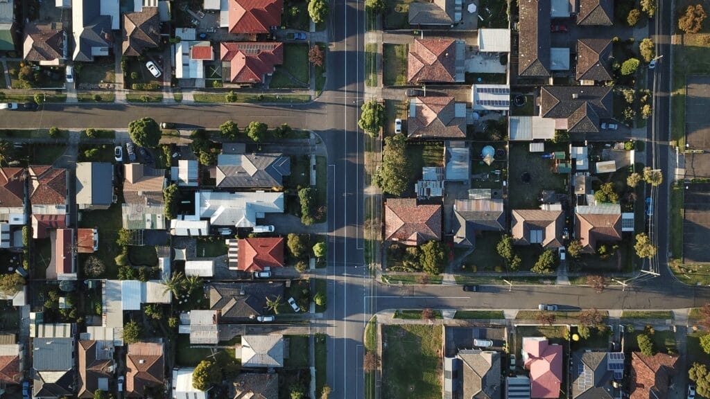 Vue aérienne d'un quartier résidentiel, montrant des maisons, des jardins et des rues paisibles.